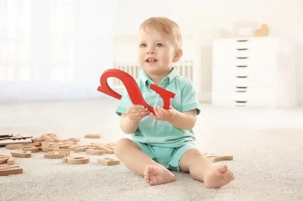 A baby boy holding the red alphabet S