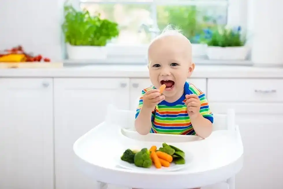 A baby enjoying solid food in his highchair.