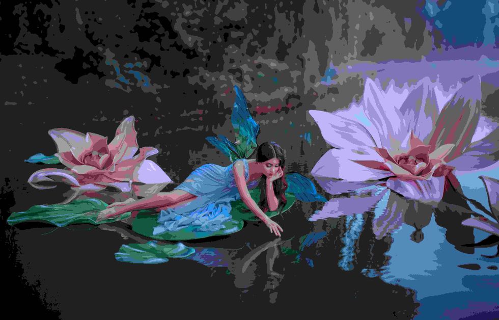 A beautiful woman a little cute fairy with butterfly wings lies on green water lily leaf