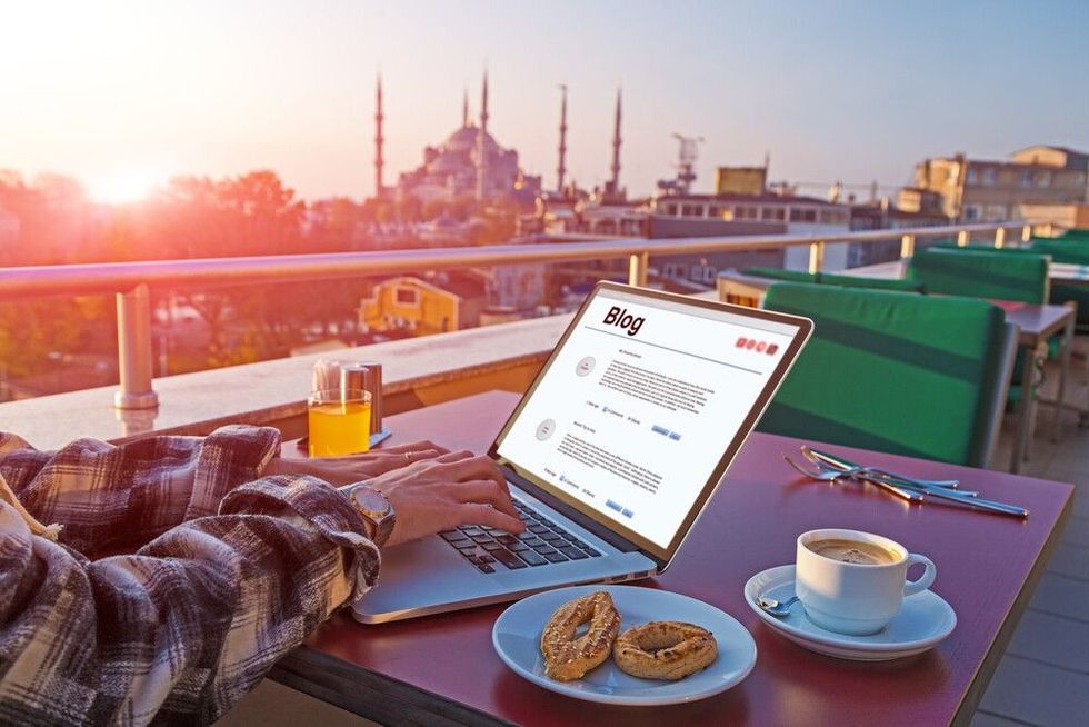 A Blogger working on Laptop Computer at Roof Top Cafe sitting at table with Coffee and Cookies.