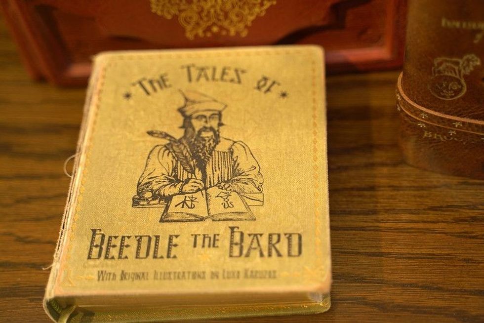 A book titled 'The Tales Of Beedle The Bard' positioned on a wooden surface.