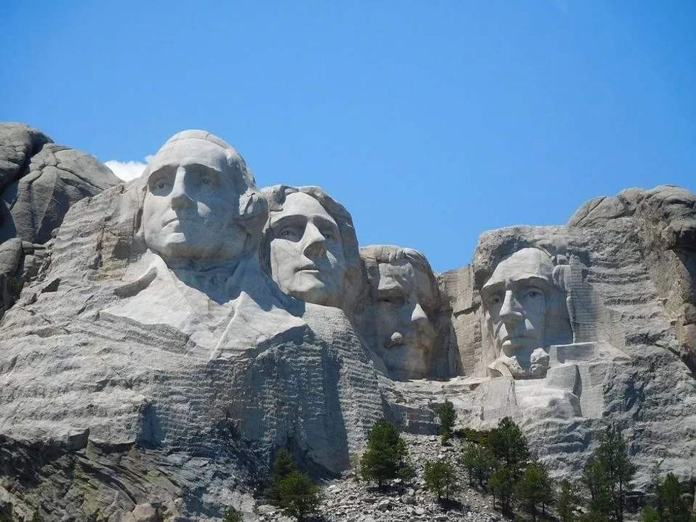A clear day view of Mount Rushmore showing the carved faces of four American presidents including Theodore Roosevelt.