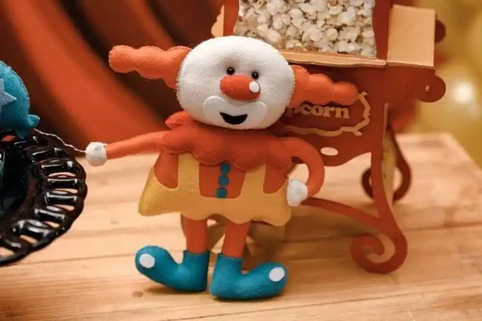 A clown toy kept in front of toy popcorn cart