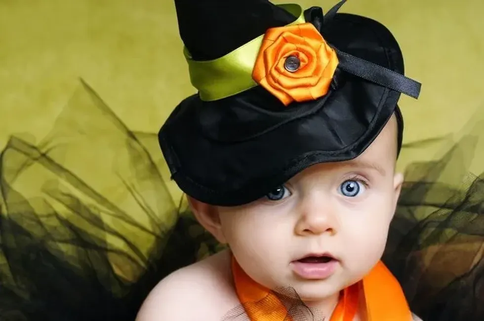 A cute baby girl wearing black hat with orange flower