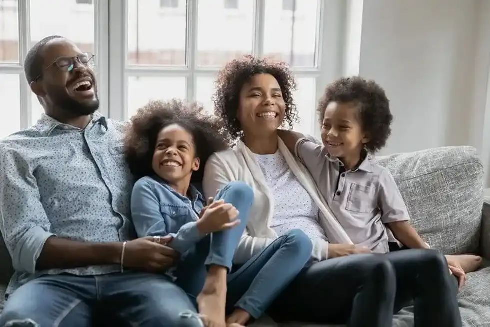 A family sat on the sofa laughing, an ideal inspiration for 'what do you call a man' jokes.