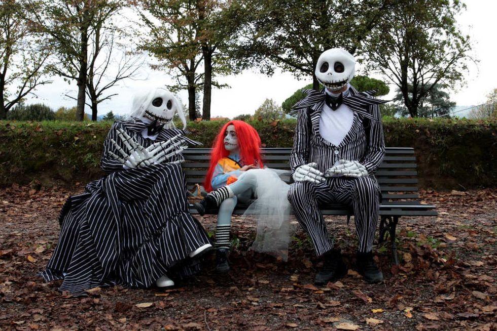 A family sitting on a bench disguised as characters from the movie Nightmare Before Christmas 