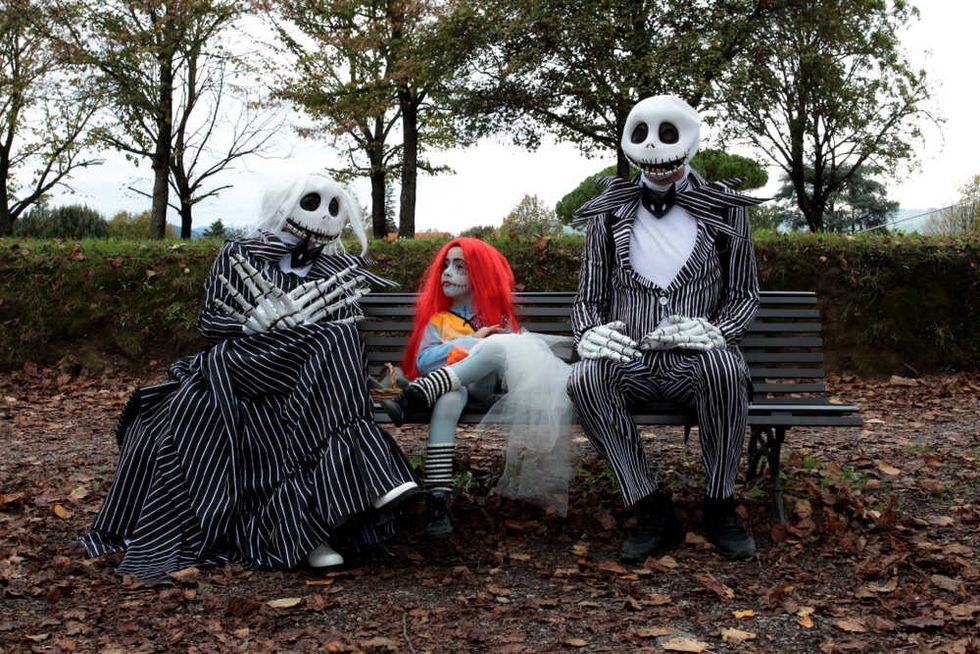 A family sitting on a bench disguised as characters from the movie Nightmare Before Christmas 