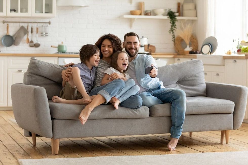 A family sitting on a sofa smiling and having fun.