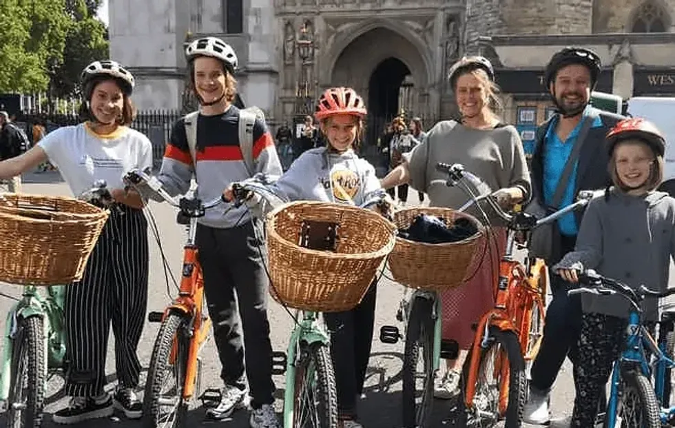 A family standing with their bikes in front of Westminster Abbey. 