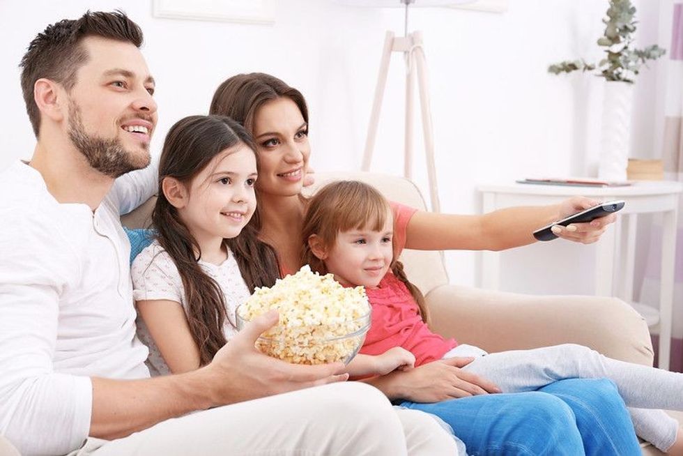 A family watching a movie with smiles on their faces
