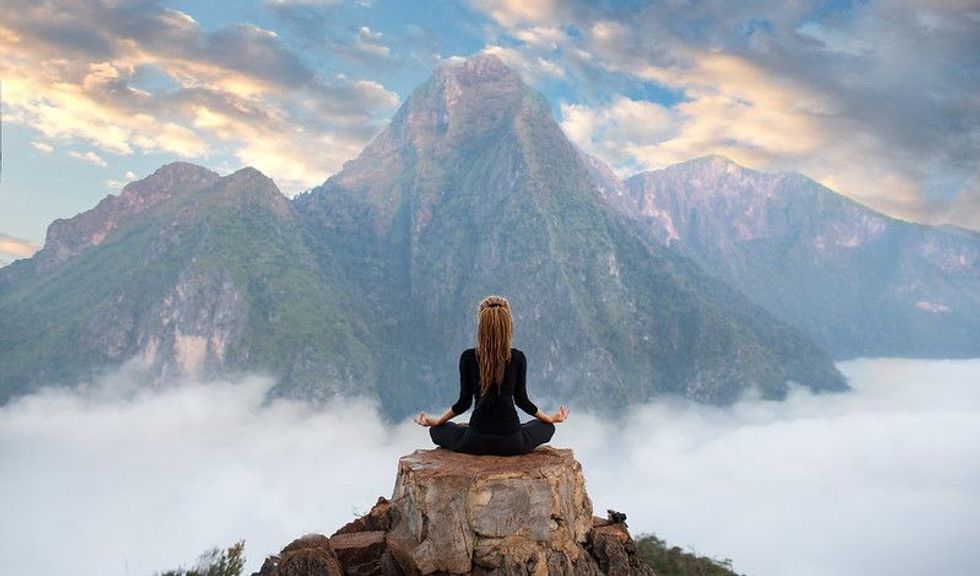 A female meditating in the midst of mountains