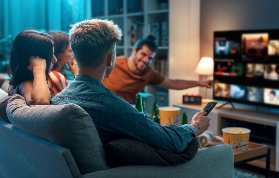 A group of friends sitting together watching tv  