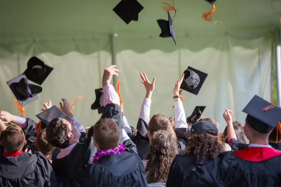 A group of teenagers throwing their graduation caps into the air.