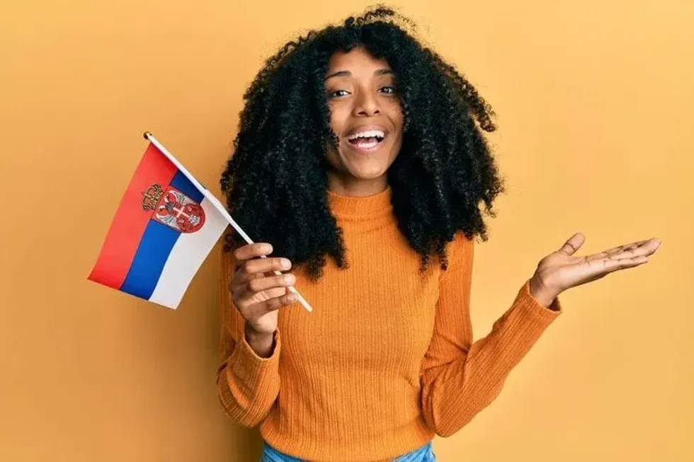 A happy woman holding the flag of Serbia