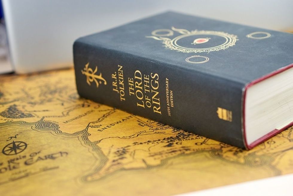 A Hardcover book of the lord of the rings novel by J.R. R. Tolkien sitting on a map on a table