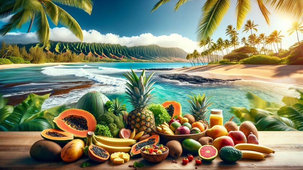 A Hawaiian landscape with vegan foods in the foreground, including pineapples, papayas, and bananas, against a backdrop of a sunny beach, clear blue waters, and palm trees.