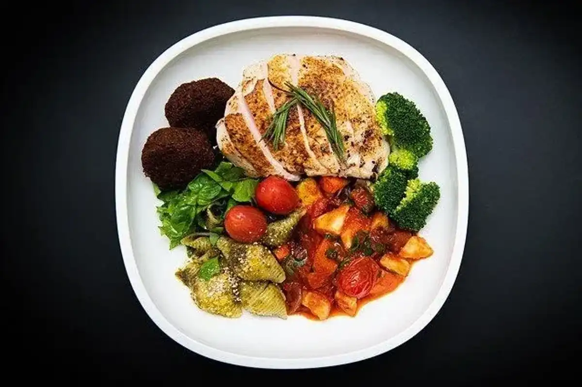 A healthy lunch plate with grilled chicken, falafel, mixed vegetables, and salad, perfect to accompany lunch quotes about the importance of a midday meal.