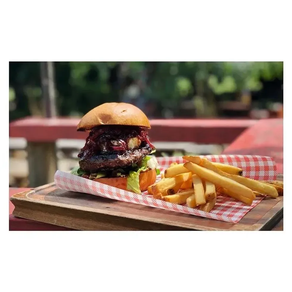 A juicy burger with beetroot topping and a side of fries presents a flavorful moment in food trivia.