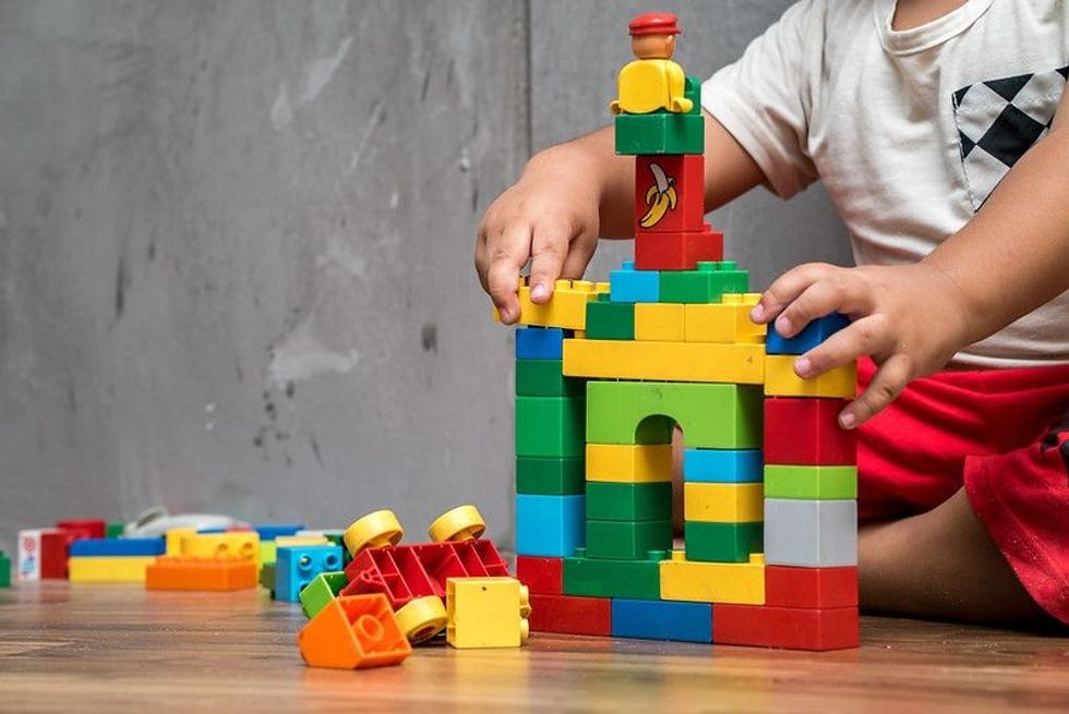 A kid building house from plastic lego blocks