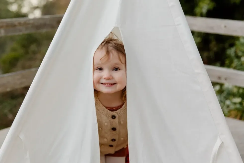 A little girl hiding in a white tent