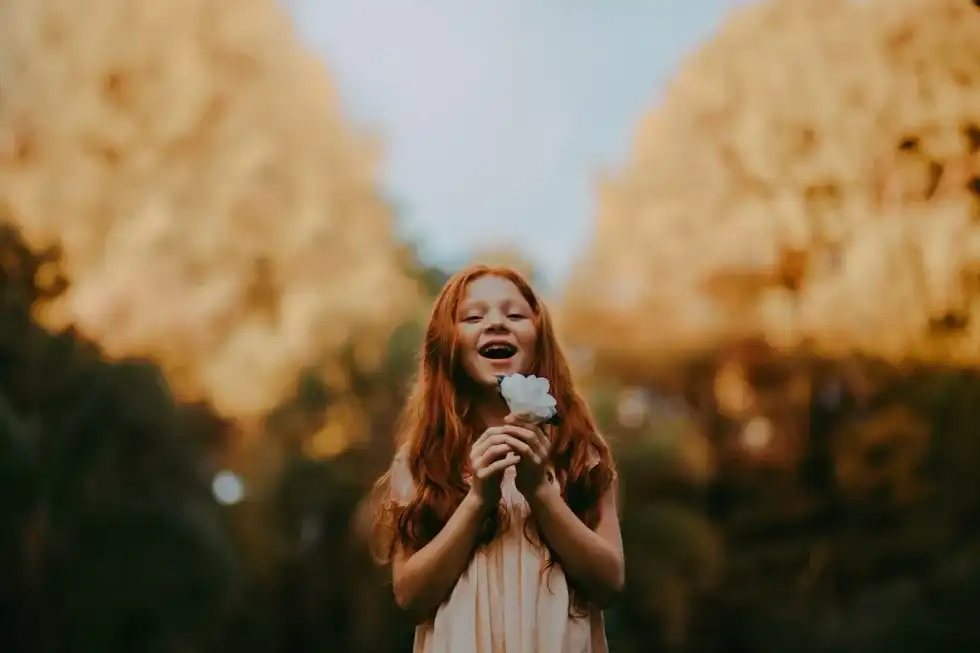 A little girl holding a white flower in her hand