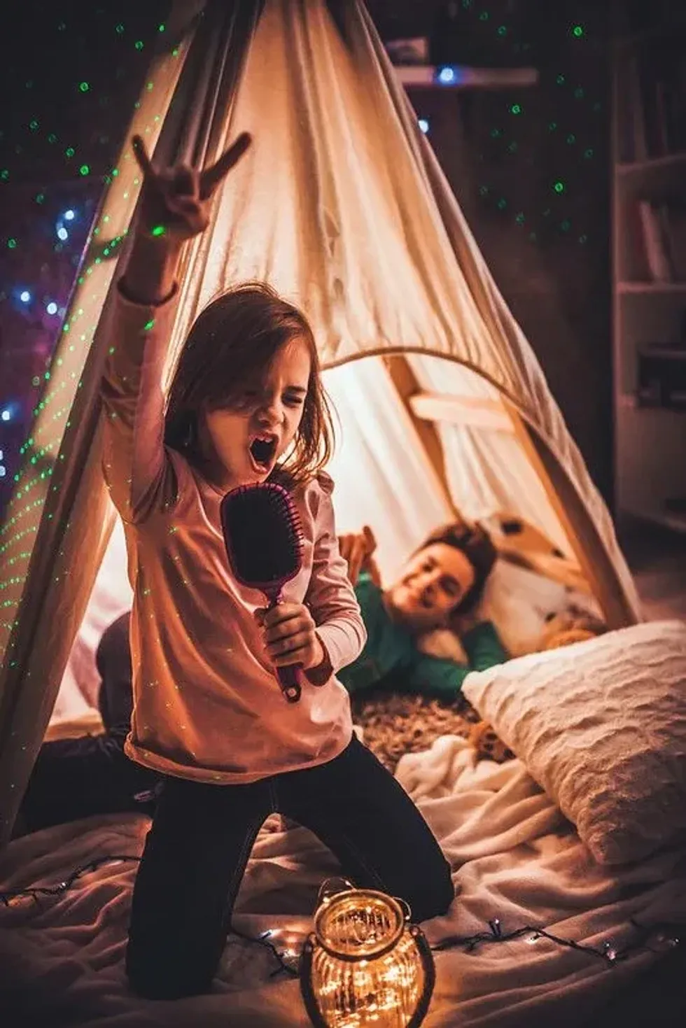A little girl singing and having fun in a sleepover setting