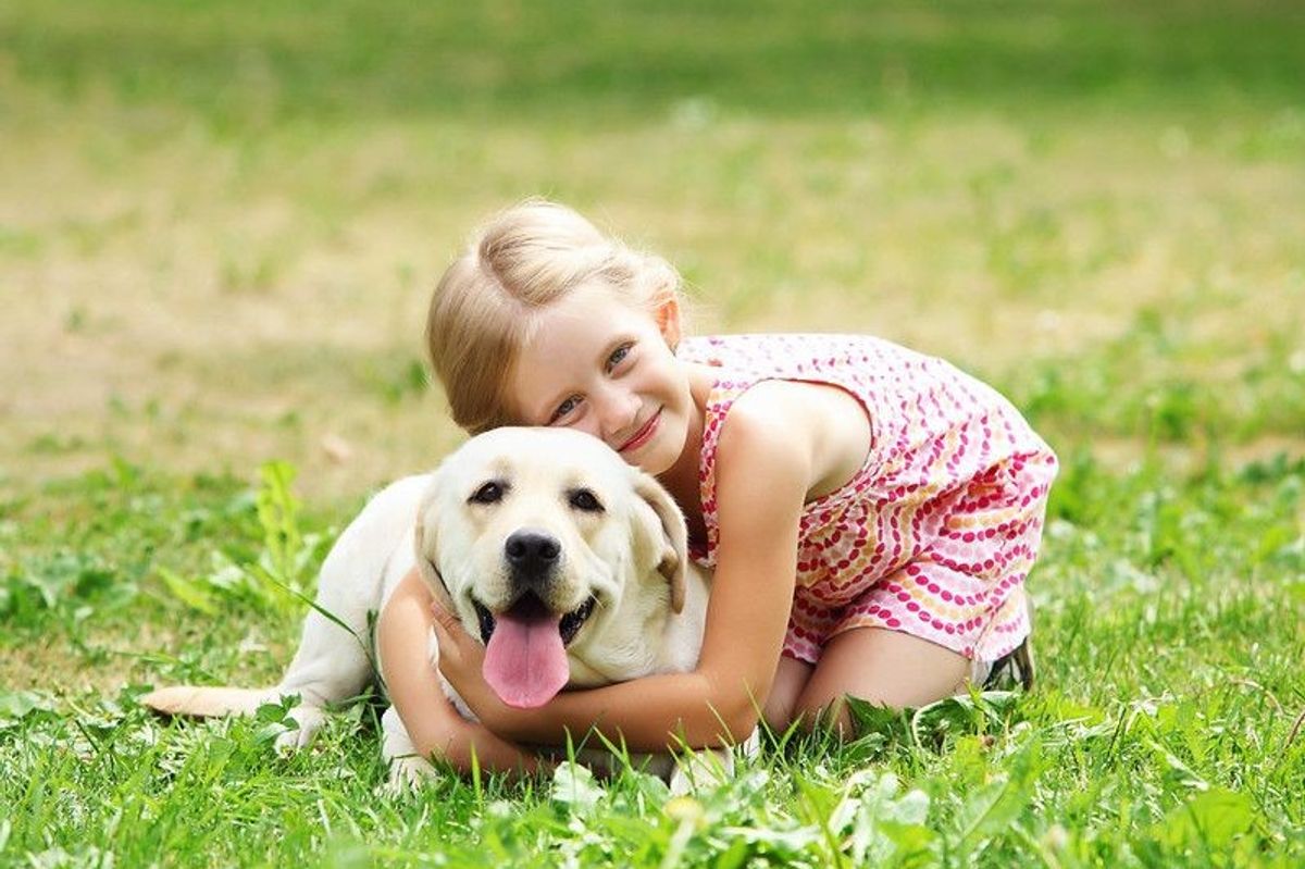A little girl with her pet dog outdoors in a park, sparking ideas for boy and unique names for girls and pets.