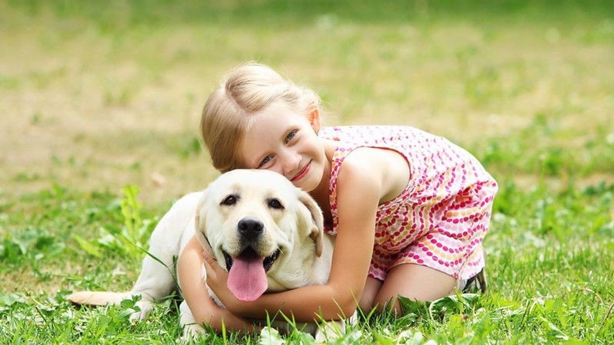 A little girl with her pet dog outdoors in a park, sparking ideas for boy and unique names for girls and pets.