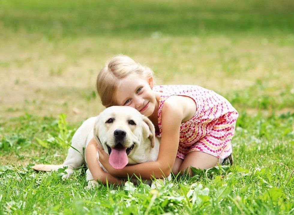 A little girl with her pet dog outdoors in a park.