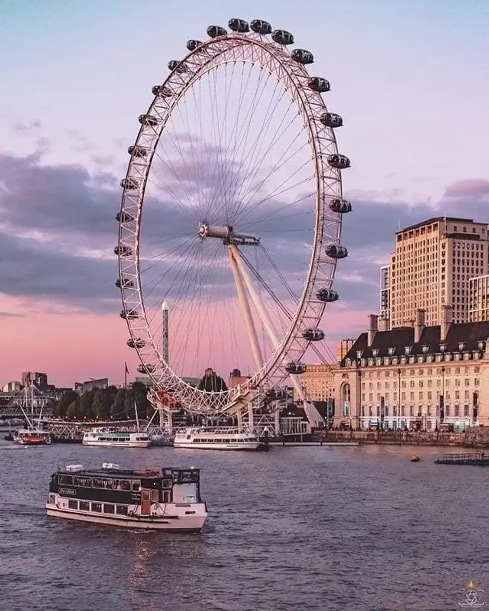 A London Eye River Cruise boat sailing on the Thames in front of the London Eye.