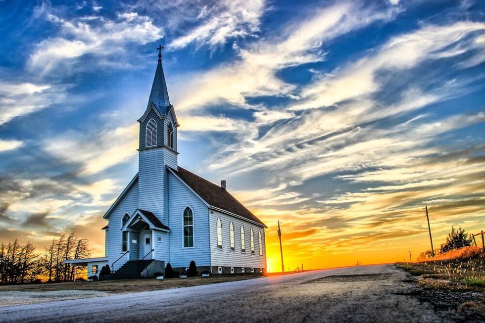 A Lone Wooden Church at Dusk with Sunset Clouds in Kansas American Midwest Prairie.