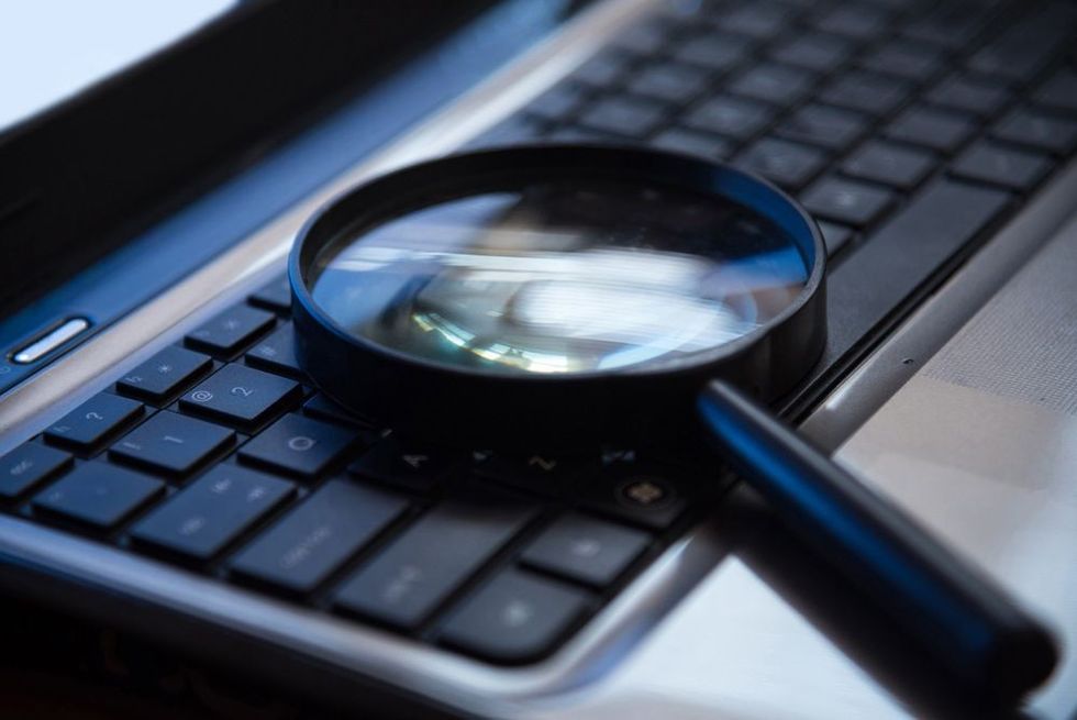 A magnifying glass placed on a keyboard of a laptop