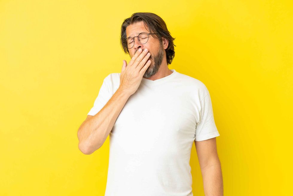 A man yawning while covering his mouth with his hand