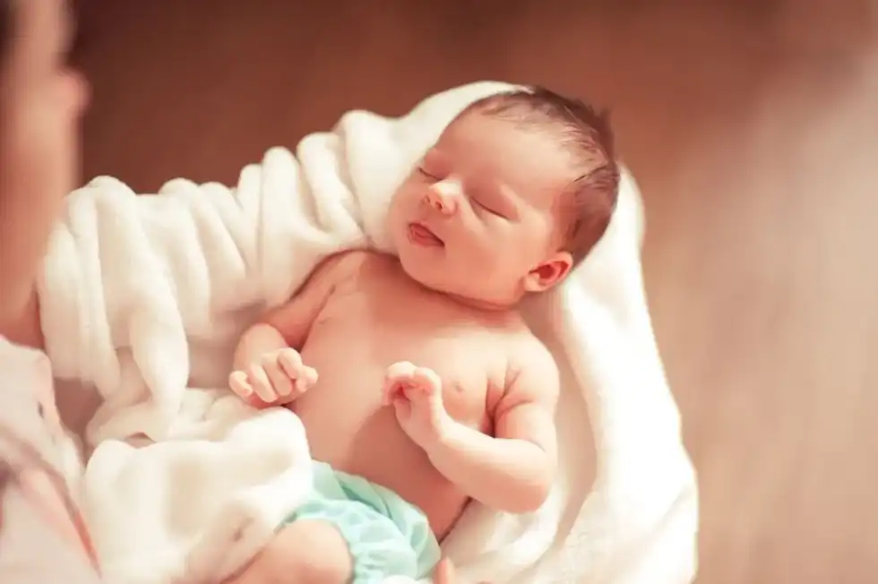 A newborn baby boy sleeping in the arms of his mother