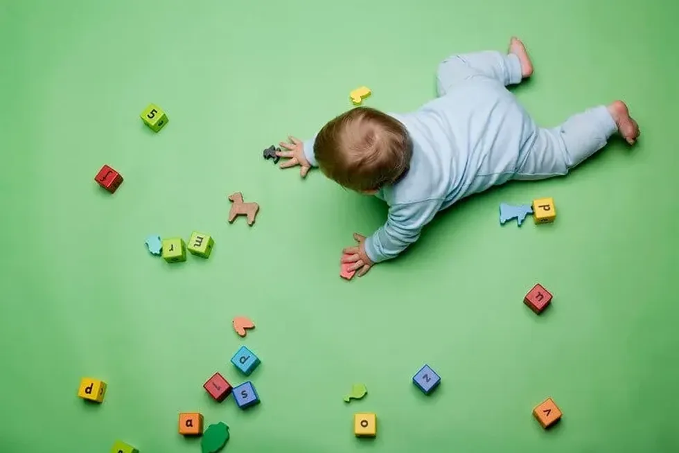 A newborn baby crawling between alphabet blocks