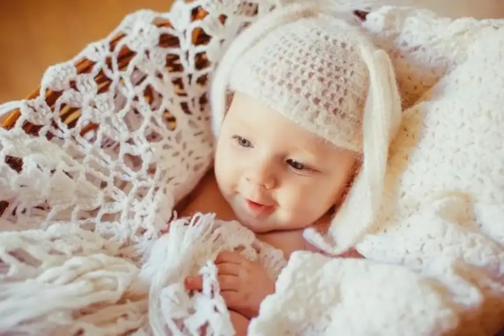 A newborn baby girl in a white knitted blanket