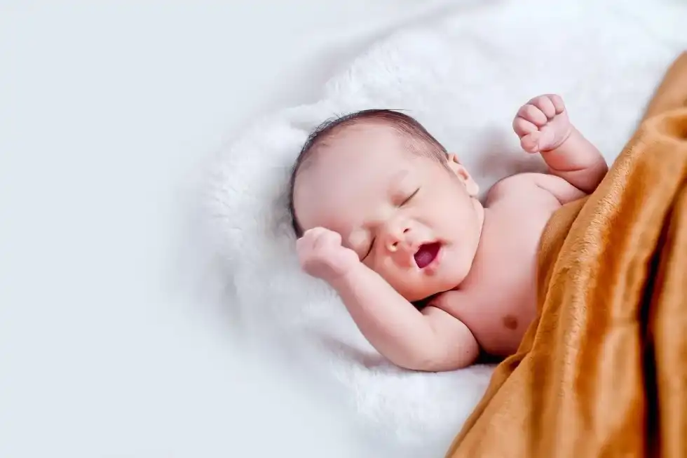 A newborn baby yawning in a brown blanket