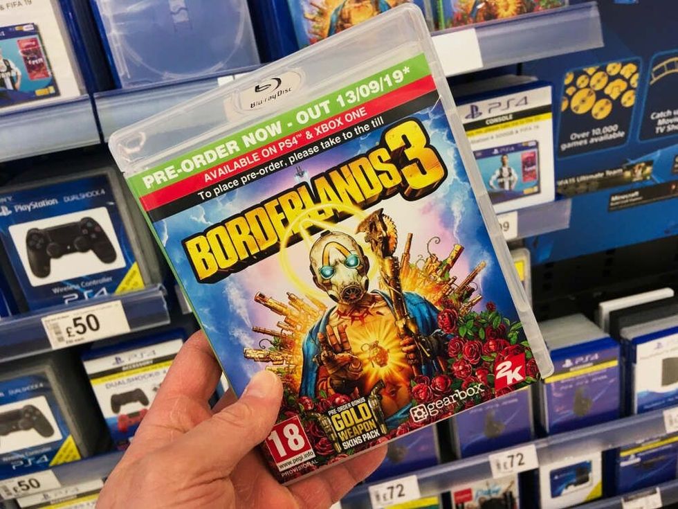 A person holding the video game borderlands 3 in a store.