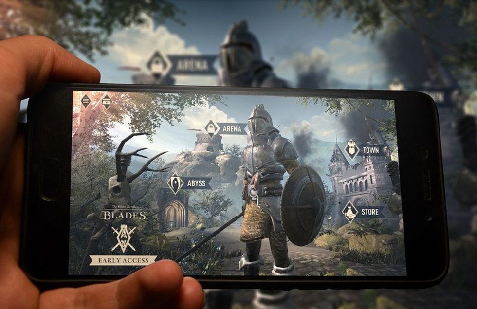A person holds up a cell phone displaying a sword game. 