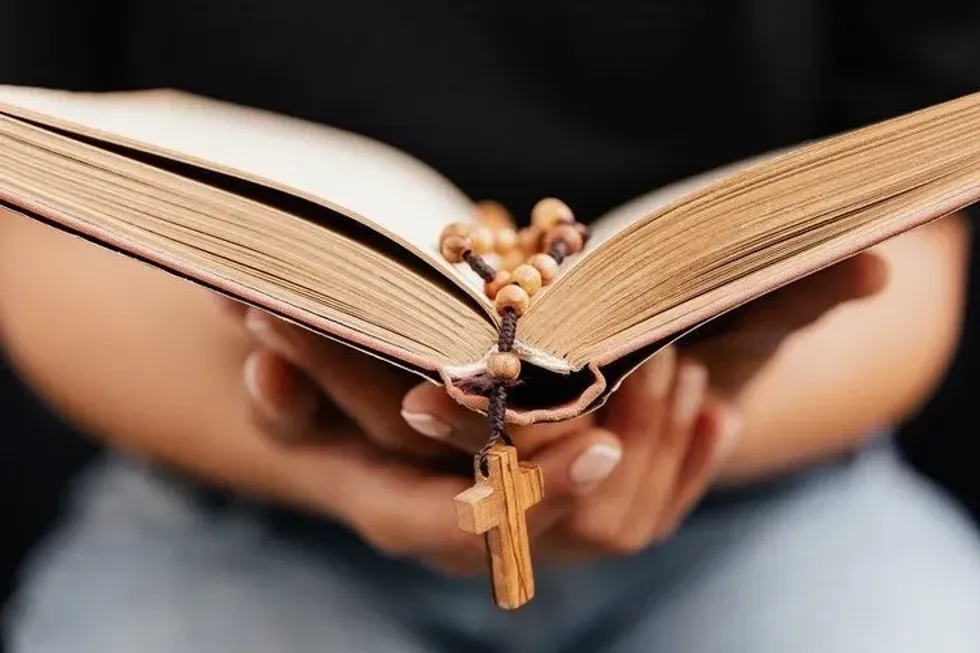 A person reading a book with rosary