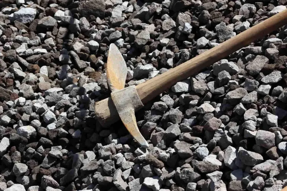 A pickaxe lying on a bed of gravel.
