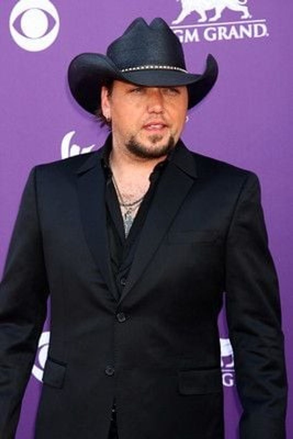 A picture of Jason Aldean wearing a black shirt, suit, and hat