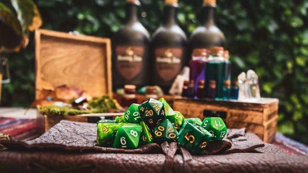 a pile of green RPG gaming dice on top of a leather-bound book