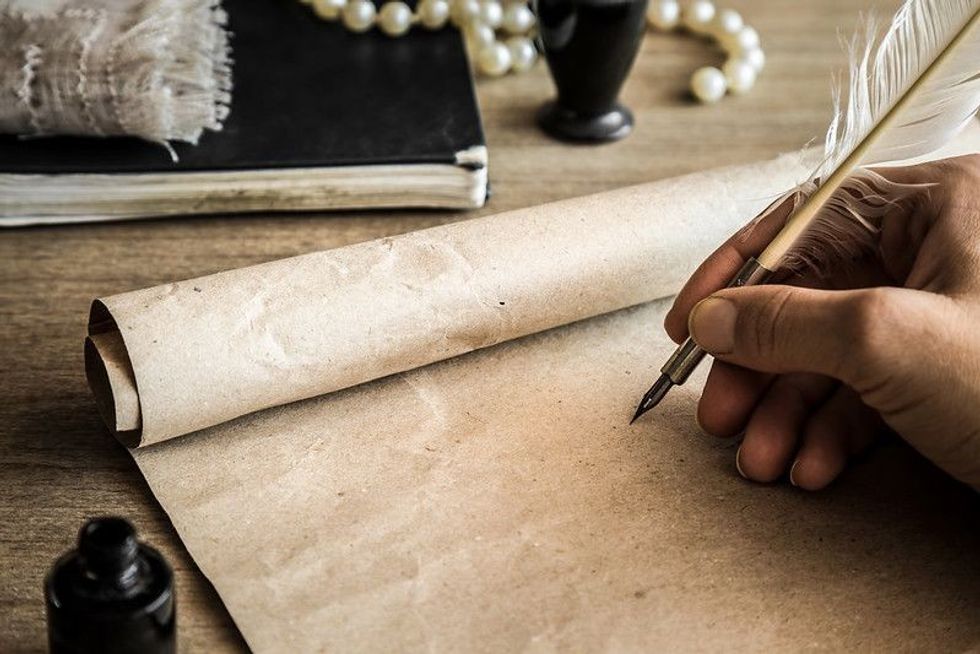 A poet is writing on a rustic paper with ink pen
