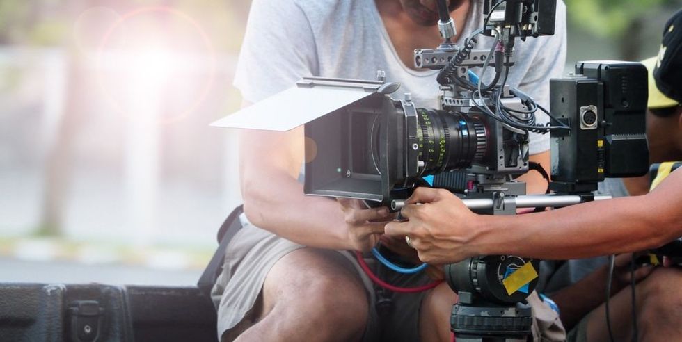 A professional filmmaking camera on shoot being operated by a man