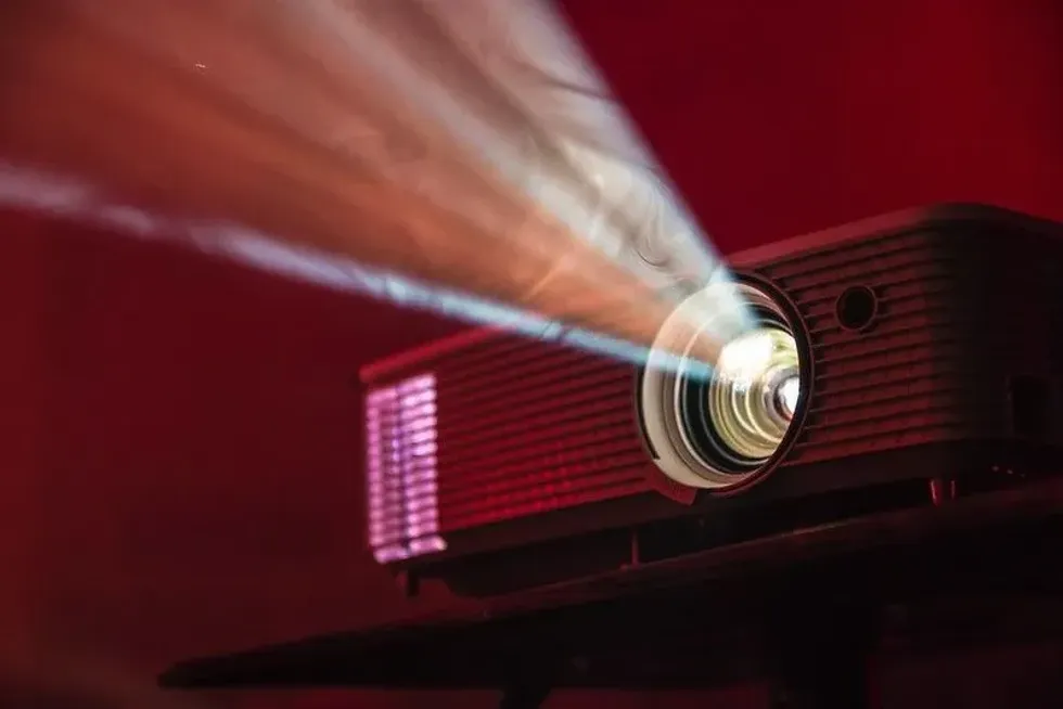 A projector set up for movie night, with light beaming brightly from it
