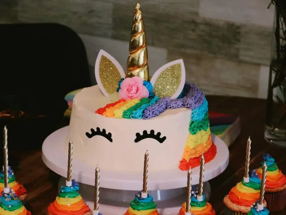 A rainbow unicorn cake with a face drawn on the side in decoration. This is a recipe kids will love.