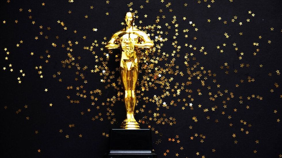 A shining Oscar award against a black background dotted with golden stars, highlighting Academy Award Facts.
