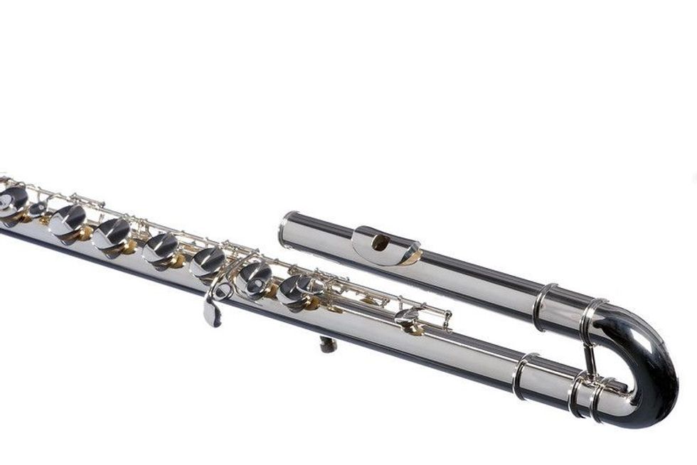 A silver bass flute isolated against a white background 