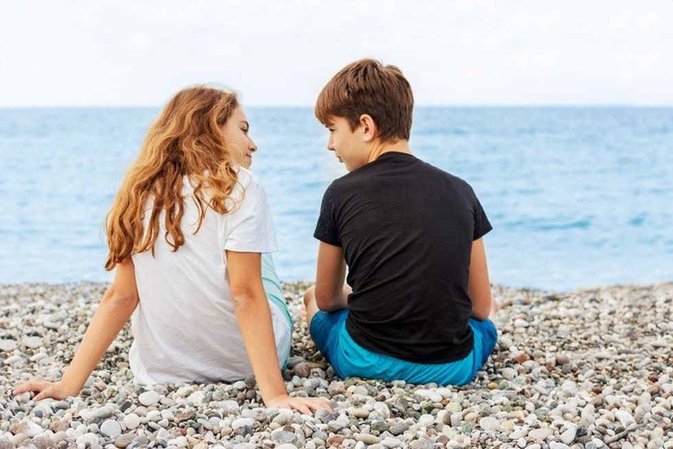 A teen couple chilling on a beach